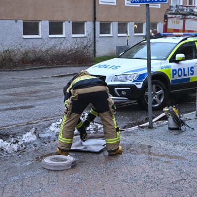 Två poliser undersöker en plats där det avfyrats skott i Bagarmossen i Stockholm.