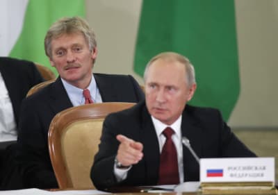 Putins talesman Dmitrij Pdeskov strax bakom president Putin under en konferens i Sotji den 11 oktober 2017.