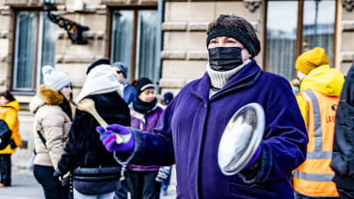 En kvinna slår i ett kastrullock under en demonstration i Åbo. 