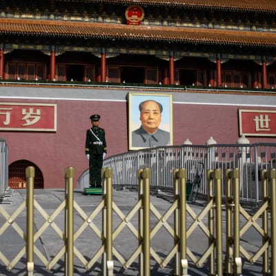 En polis står framför ett porträtt av Mao vid ingången till den förbjudna staden i Peking. 