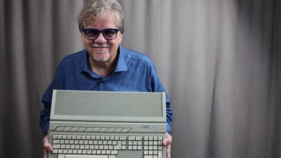 Mikko Alatalo hymyilee kameralle ja esittelee vanhaa Atari tietokonetta.