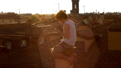 Italienska studenten Pierpaolo Mazzurco läser på taket till studentlägenheten i Bologna under coronakarantänen.