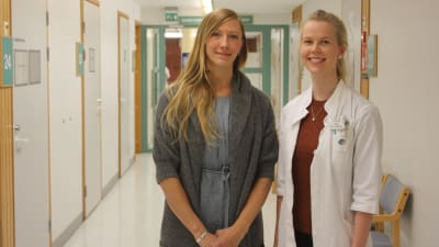 Två kvinnor i en hälsocentralskorridor.
