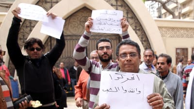 Demonstranter utanför Mar Girgis-kyrkan i Tanta med lappar där de bl.a. kräver att guvernören, säkerhetschefen och inrikesministern ska sparkas.