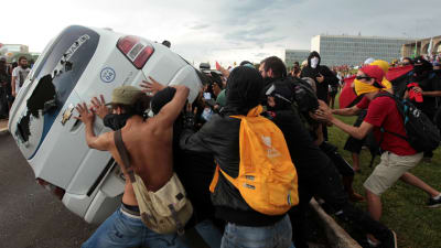 Demonstranter välter omkull en bil i Brasilia 29.11.2016