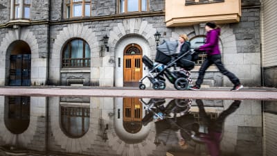 Två unga mammor med barnvagn promenerar i Åbo invid en stor vattenpöl