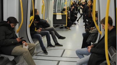 Passagerar på tåg kollar sina mobiltelefoner.