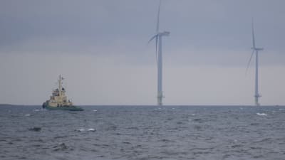Bogserbåt vid Vetenskär med vindkraftsverk i bakgrunden.