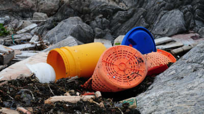 Plasthinkar som ligger och skräpar på en strand.
