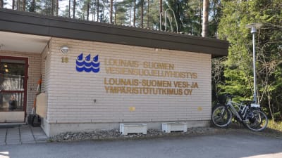 En tegelhusvägg med texten Lounais-Suomen vesi- ja ympäristötutkimus Oy
