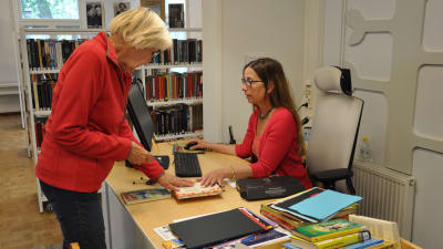 besökaren Ami Levander lånar böcker av Henrika Eklund på houtskärs bibliotek.