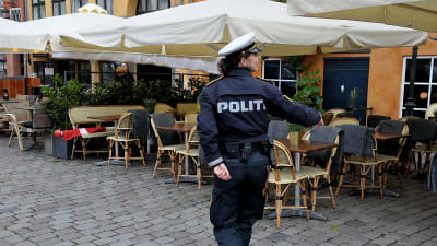 Kvinnlig polis övervakar avståndet mellan restaurangstolar i Nyhavn