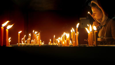 Människor lägger ner ljus vid minnesmärket för dem som dog udner revolutionen i Timisoara.