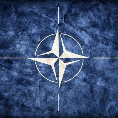 Natos flagga, en vit symbol mot blå bakgrund.