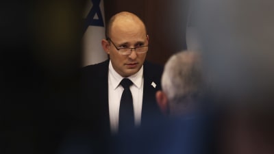 Israels premiärminister Naftali Bennett står vid ett talarpodium och håller tal.