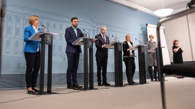 Foto på avstånd av fyra ministrar i presskonferens.