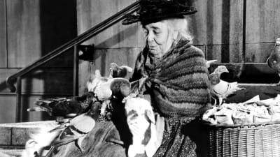 Kvinnan med fåglarna spelades av Jane Darwell. Här poserar hon med fåglarna i Mary Poppins.