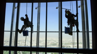 Två migrant arbetare tvättar fönster i Aspire Tower som är en av de högsta byggnaderna i Qatar.