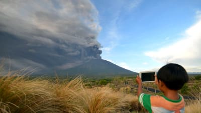 En pojke fotograferar rökmolnet från vulkanen Agung i Kubu, Bali, den 26 november. 