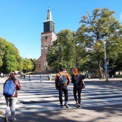 Tre unga går över ett övergångsställe vid Åbo Domkyrka.