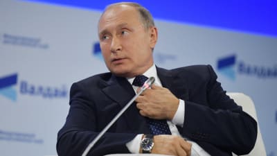 Vladimir Putin lyssnar och rättar till slipsen vid Valdaj-Mötet 2018.