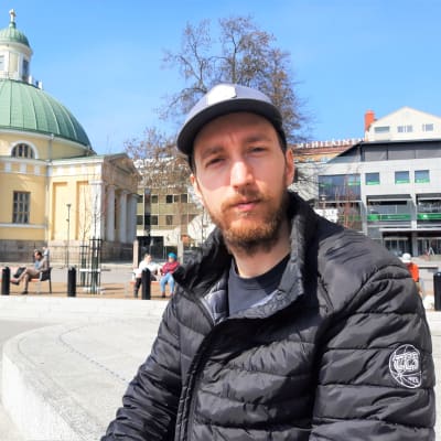 En man sitter på en bänk på Salutorget i Åbo. 