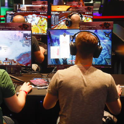 Två män sitter framför varsin dataskärm och spelar. Männen sitter med ryggen mot kameran
