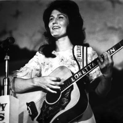 Countryartisten Loretta Lynn spelar gitarr. Bilden är svartvit och på dne syns Loretta Lynn som ung.