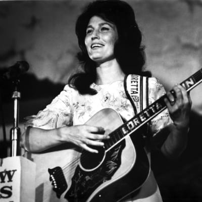 Countryartisten Loretta Lynn spelar gitarr. Bilden är svartvit och på dne syns Loretta Lynn som ung.