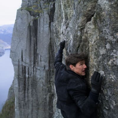 Ethan Hunt (Tom Cruise) klänger sig fast på en hög klippvägg.