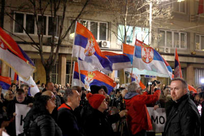 En folkmassa protesterar med flaggor i händerna.