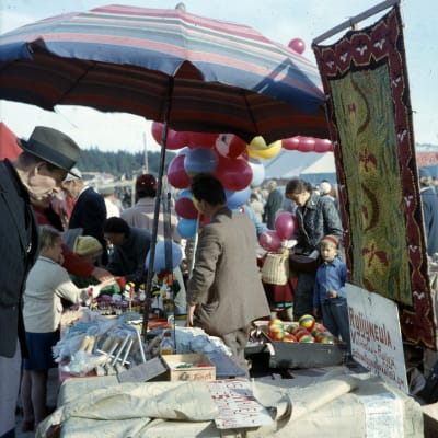 En man synar utbudet vid ett marknadsstånd. I bakgrunden syns ballonger.