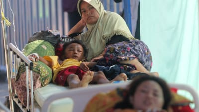 En mamma transporterar sin skadade son till ett sjukhus i Tanjung, i norra Lombok, Indonesien. 
