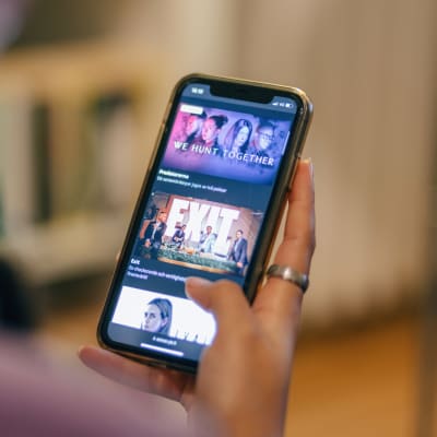 En person håller i en telefon som visar Yle Arenans innehåll på skärmen.