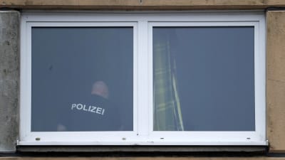 Fönster till razzialägenheten, där en polisman syns genom fönstret. 