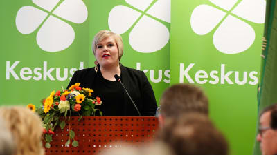 Annika Saarikko håller tal på Centern partifullmäktige. I bakgrunden Centerns logotyp.