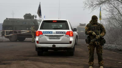 Ett OSSE-märkt fordon passerar en ukrainsk soldat på väg mot gränsposteringen Majorsk. OSSE övervakade fångutväxlingen. 