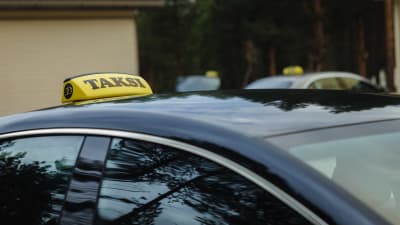 En svart taxi med gul skylt på taket. 
