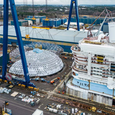 Jättimäinen lasi- ja teräsrakennelma, Dome-nimen saanut kupu Meyer Turun telakalla Icon of the Seas -aluksen vierellä.