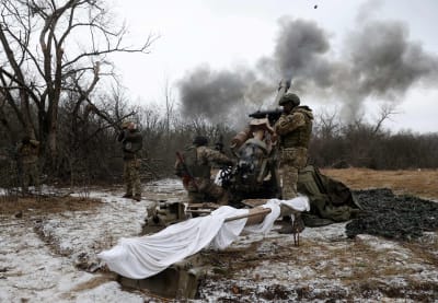 Ukrainska soldater avfyrar en L119-haubits mot Ryssland ute i terrängen. 
