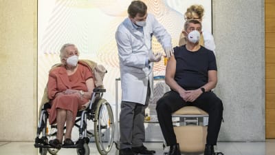 Tjeckiens premiärminister får coronavaccin. Bredvid honom står en sjukskötare och en äldre dam i rullstol.