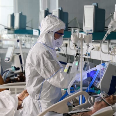 En sjukskötare i skyddsutrustning vårdar patienter på coronaintensiven.