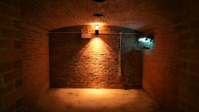 Tegelvägg i källaren som är upplyst av lampor