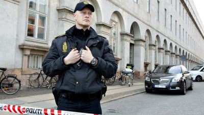 En ensam dansk polis står vid avspärrningsband på tom gata i Köpenhamn.