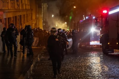 Kravallpoliser avancerar längs en gata.