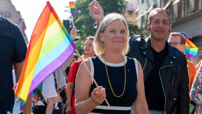 Magdalena Anderson håller i en regnbågsflagga på prideparad i Stockholm.