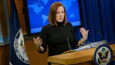 Jen Psaki står vid ett talarpodium och pratar.
