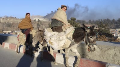 Förbipasserande afghaner ser på hur hotell Intercontinental brinner på en kulle