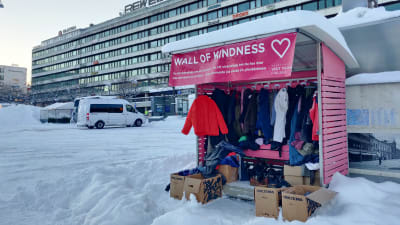 En rosa busskur fylld med kläder som folk har donerat står på Vasa torg. Det är vinter och snö omkring.