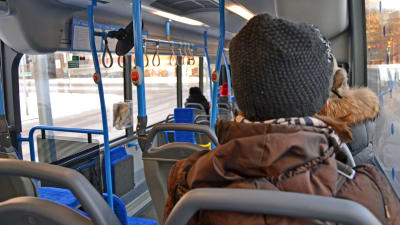 Bild inifrån en stadsbuss. Man ser flera tomma säten och några passagerare.